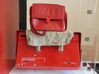 848922 Afbeelding van een rode PTT-brievenbus, -postzak en -posttas behorend bij een kleine uitstalling van objecten ...